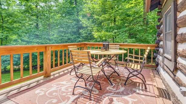 A wooden deck with a table and chairs, surrounded by a wooden railing, overlooking a forested area. - Hot Tub + Deck: Cabin Hideaway in Brown County (Nineveh)