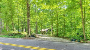 A forested area with a road, a small cabin, and a clear sky. - Hot Tub + Deck: Cabin Hideaway in Brown County (Nineveh)