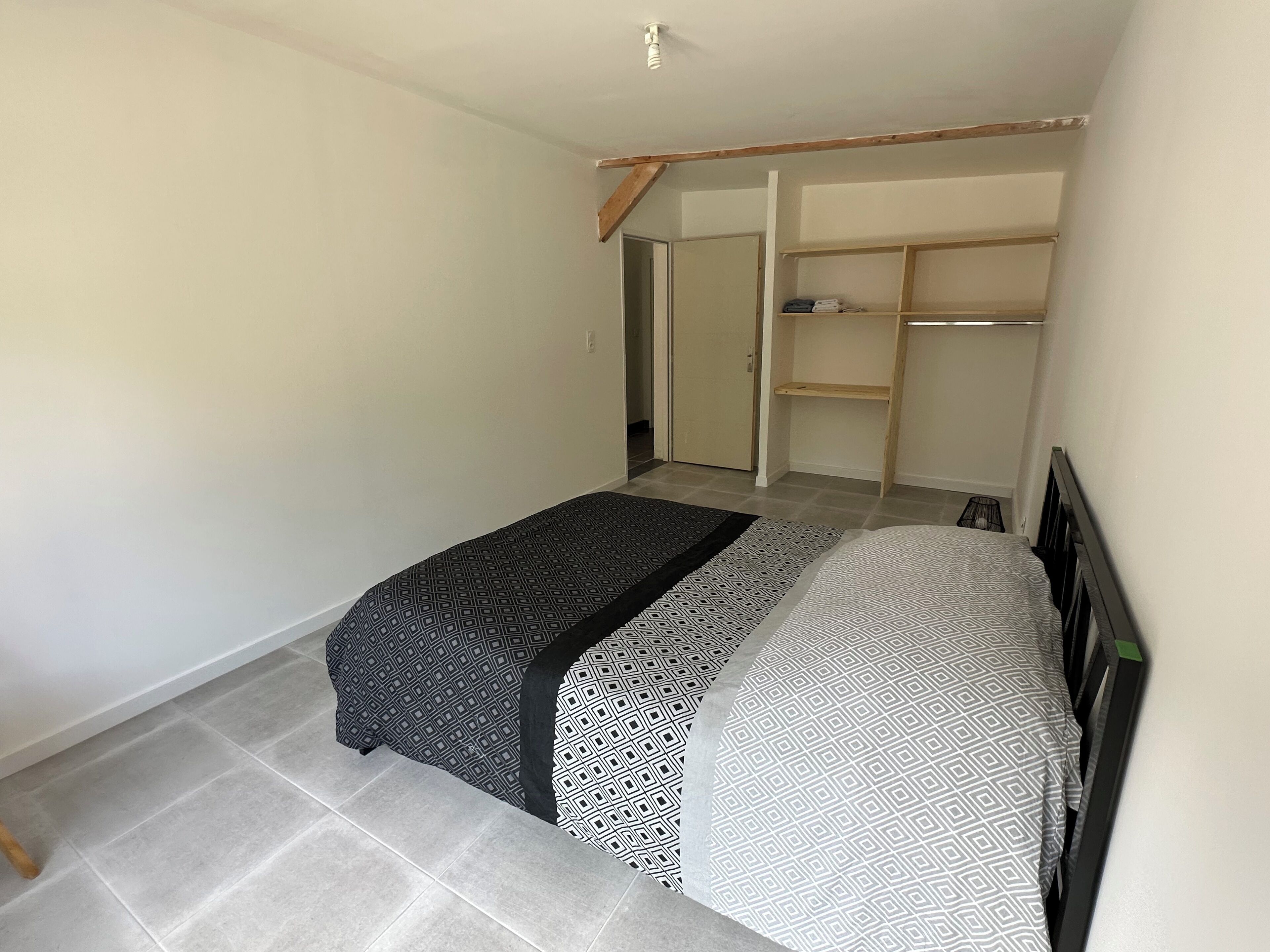 A bedroom with a bed, a wardrobe, and a door leading to another room.