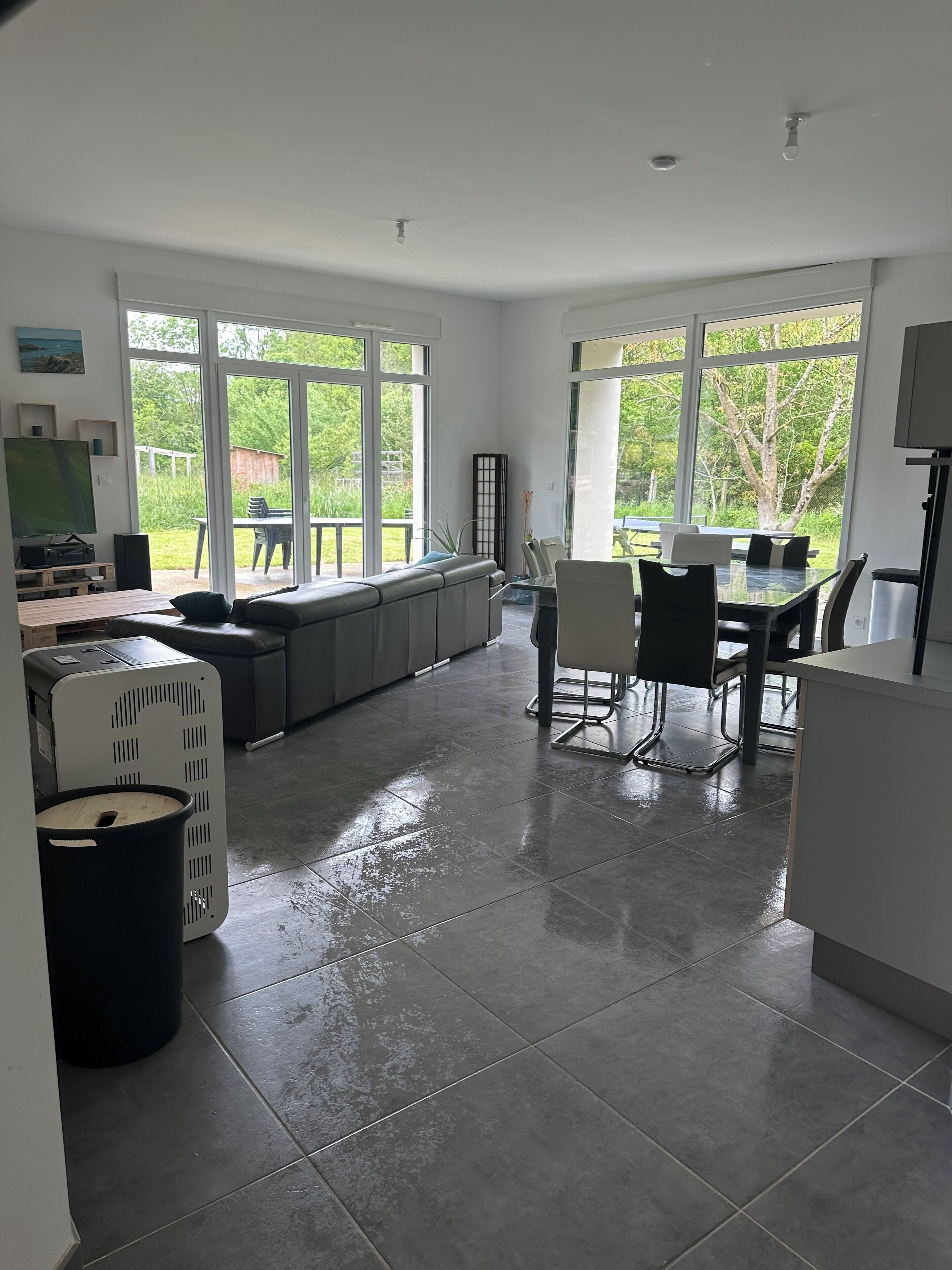 Una cocina moderna con ventanas amplias, un comedor y suelo húmedo.