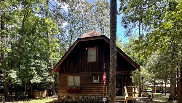 A rustic cabin with a stone pathway leading to the entrance, surrounded by trees.