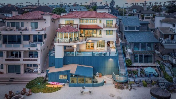 A multi-story house with a pool, balconies, and a covered outdoor area.