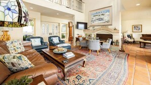 A spacious living room with a fireplace, a piano, and a large rug.