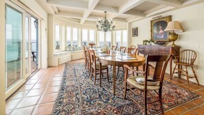 A dining area with a large round table, chairs, and a patterned rug.