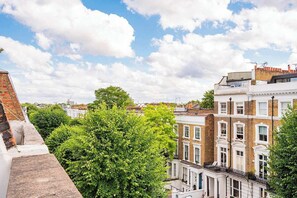 Une vue de maisons mitoyennes à étages, avec un arbre au premier plan et un ciel dégagé.