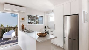 Een moderne keuken met een groot kookeiland, roestvrijstalen apparatuur en uitzicht naar buiten.