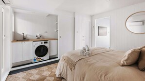 Een slaapkamer met een bed, een wasmachine en een spiegel.