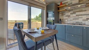 A modern kitchen with a dining area, large windows, and a view of the outdoors.