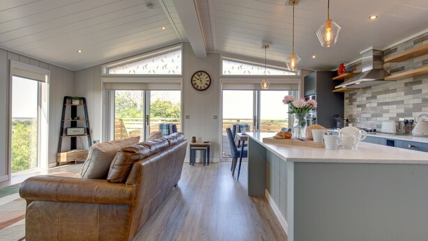 A modern kitchen with a large island, a built-in oven, and a dining area with a sofa and chairs.