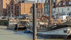 En havn med fortøjede både, en murstensbygning og et skilt med teksten 'Shop Viewpoint'.