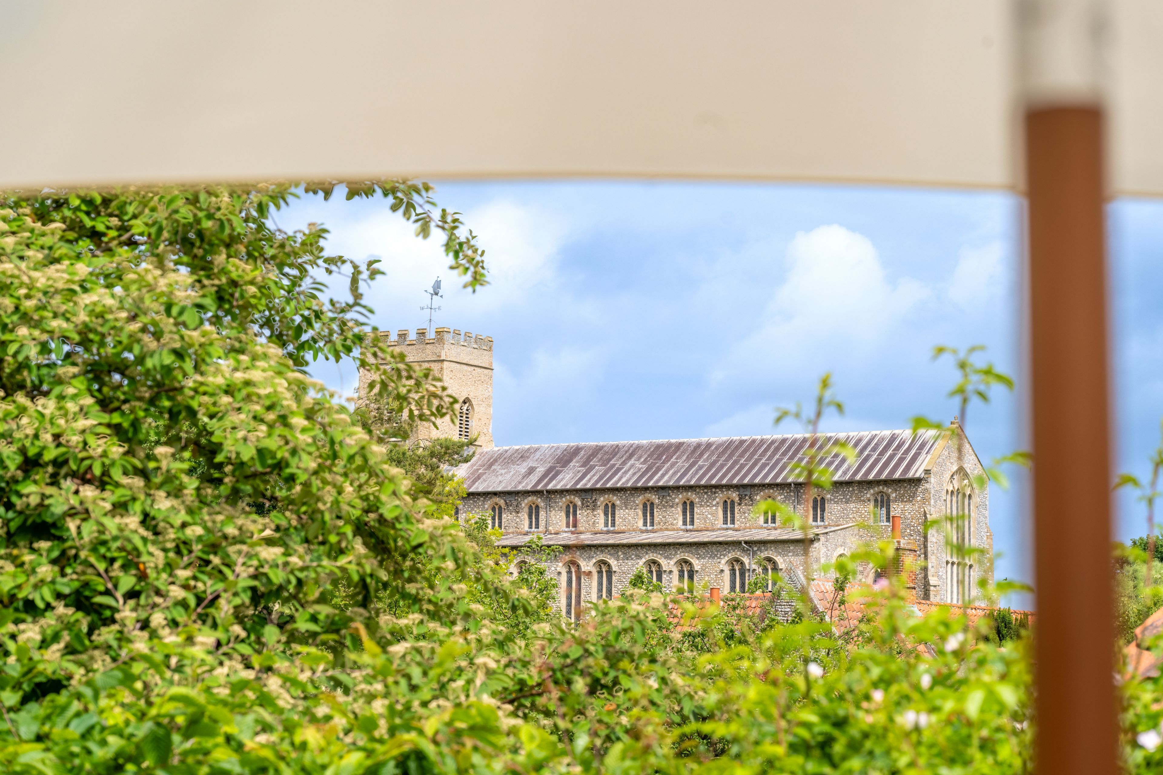A historic building with a tower and arched windows, surrounded by lush greenery.