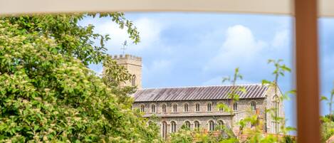 A historic building with a tower and arched windows, surrounded by lush greenery.