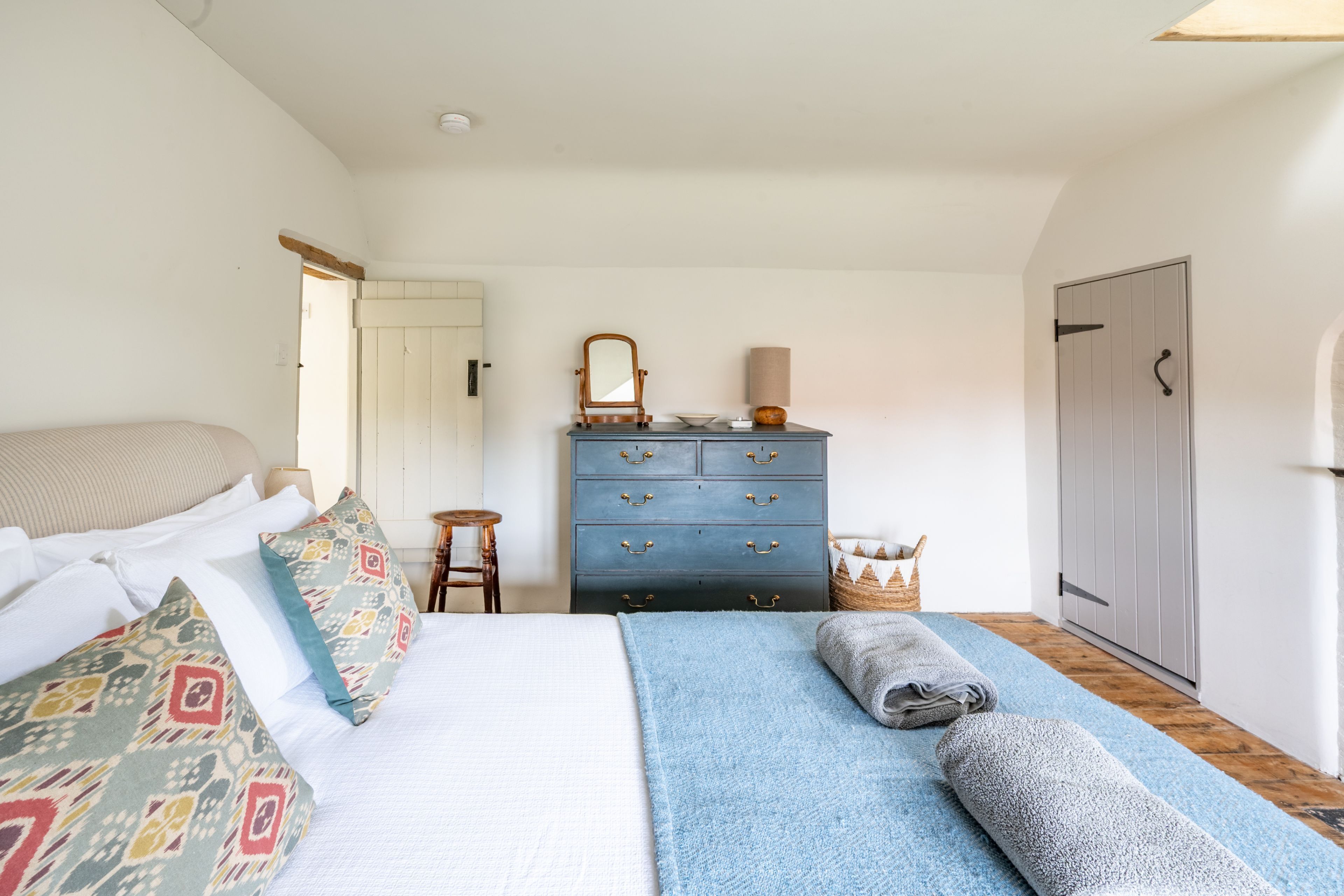 A bedroom with a bed, a dresser, a mirror, and a door.