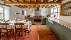 Une cuisine avec des poutres en bois, une table à manger entourée de chaises et un évier.