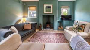 Un salon chaleureux avec une cheminée, deux canapés, un tapis à motifs et un téléviseur.