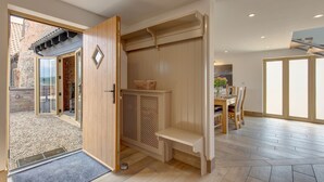Un intérieur moderne avec un banc en bois, un coin repas et une vue sur une terrasse extérieure, accessible par une porte vitrée.