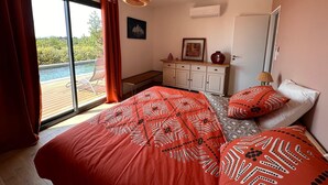 Quarto com cama grande, escrivaninha e vista para uma piscina.