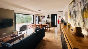 Uma sala de estar moderna com sofá, mesa de jantar e área de cozinha.