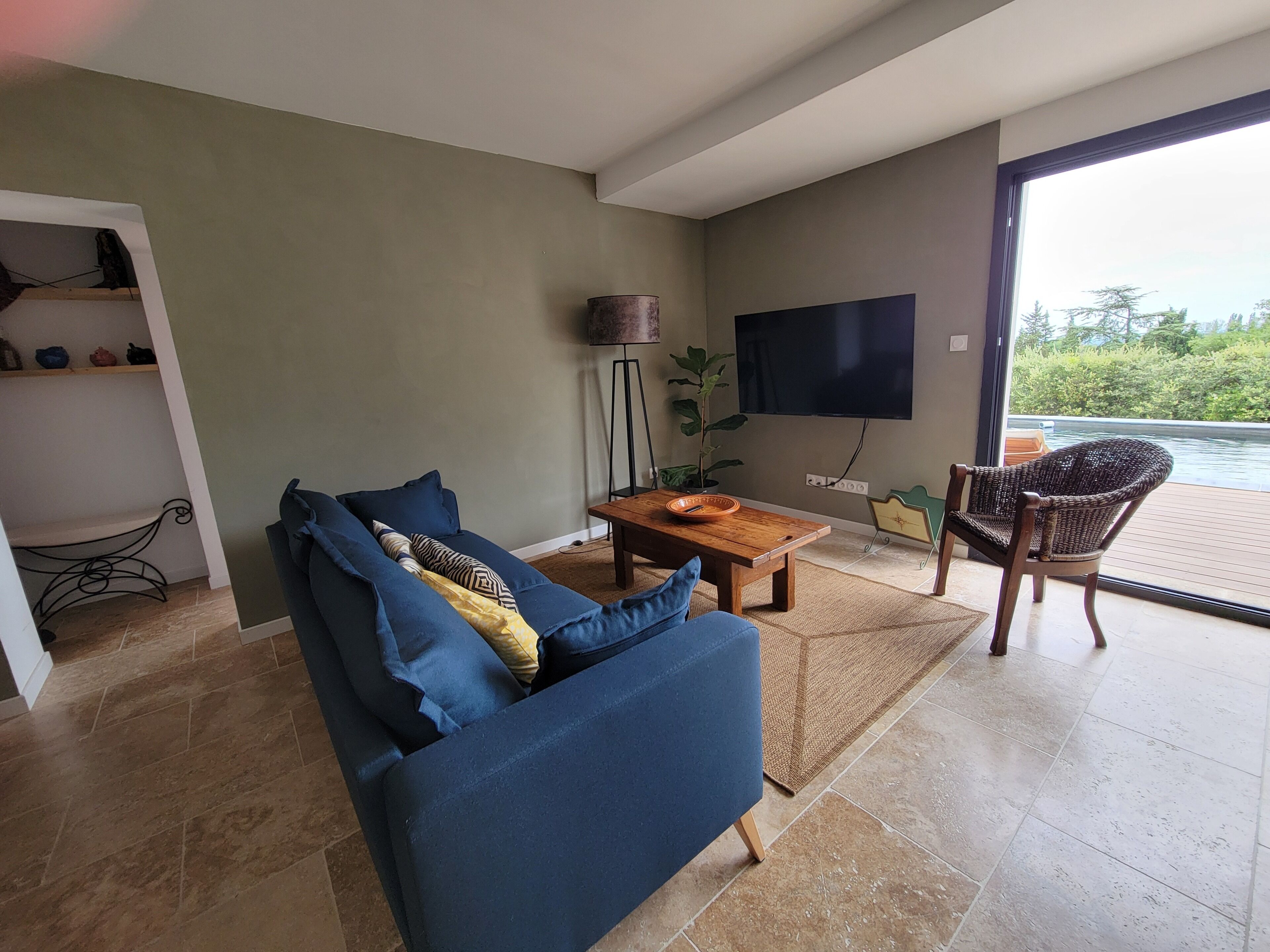 Un salon moderne avec un canapé, une table basse et une vue sur un plan d’eau, visible à travers une porte vitrée.