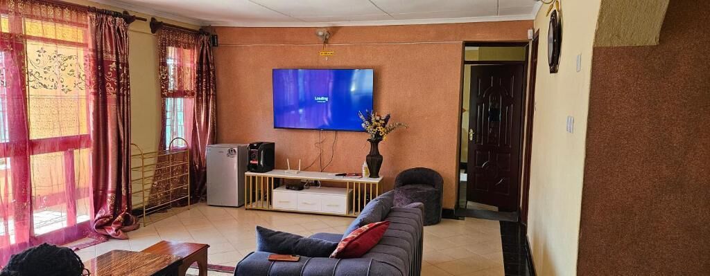 Un salón con sofá, mesa de centro, televisor y una pequeña mesa con un jarrón.
