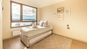 A bedroom with a bed, a window, a radiator, and wall art.
