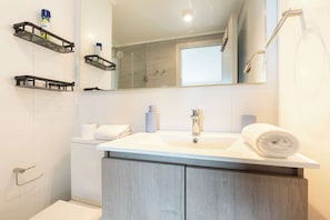 A bathroom with a white sink, a mirror, a towel, and a shower.