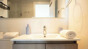 A bathroom with a white sink, a mirror above it, and a towel on the counter.