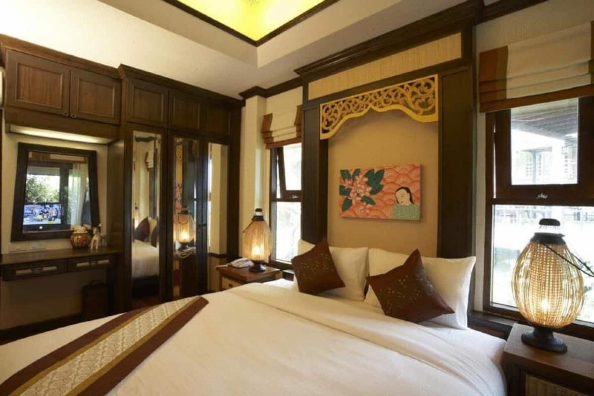 Quarto de hotel com cama grande, guarda-roupa de madeira, um quadro na parede e janela com vista.