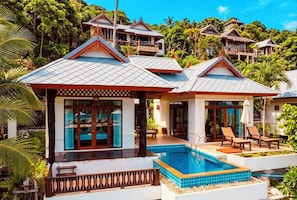 A resort with a swimming pool, lounge area, and traditional architecture.