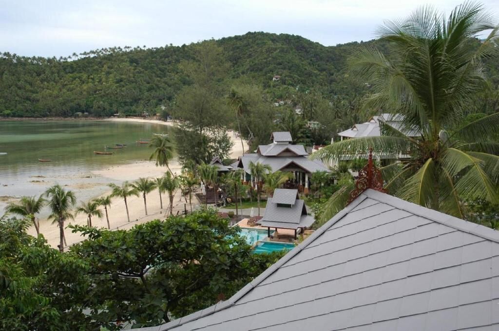 Een resort met een zwembad, strand en palmbomen.
