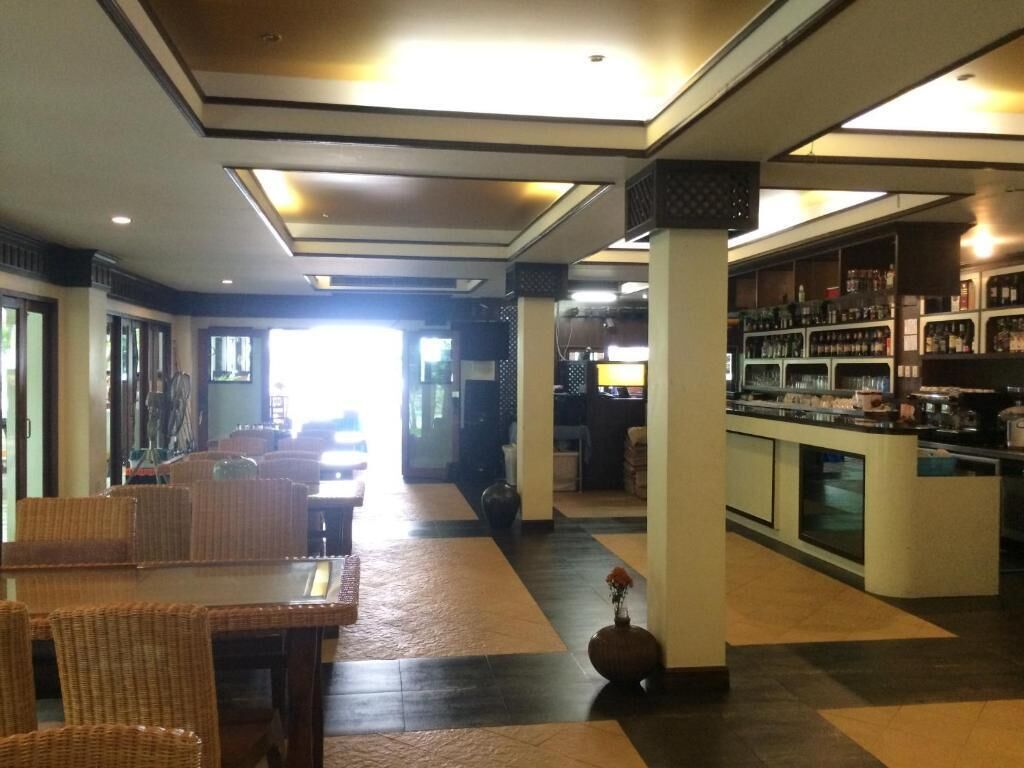A hotel lobby with a reception desk, a bar area, and a seating area with wicker furniture.