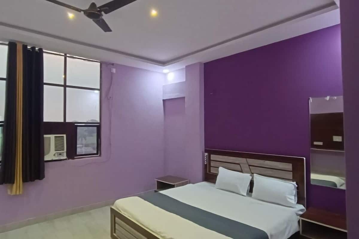 A bedroom with a bed, a ceiling fan, a window with curtains, and a wall-mounted air conditioner.