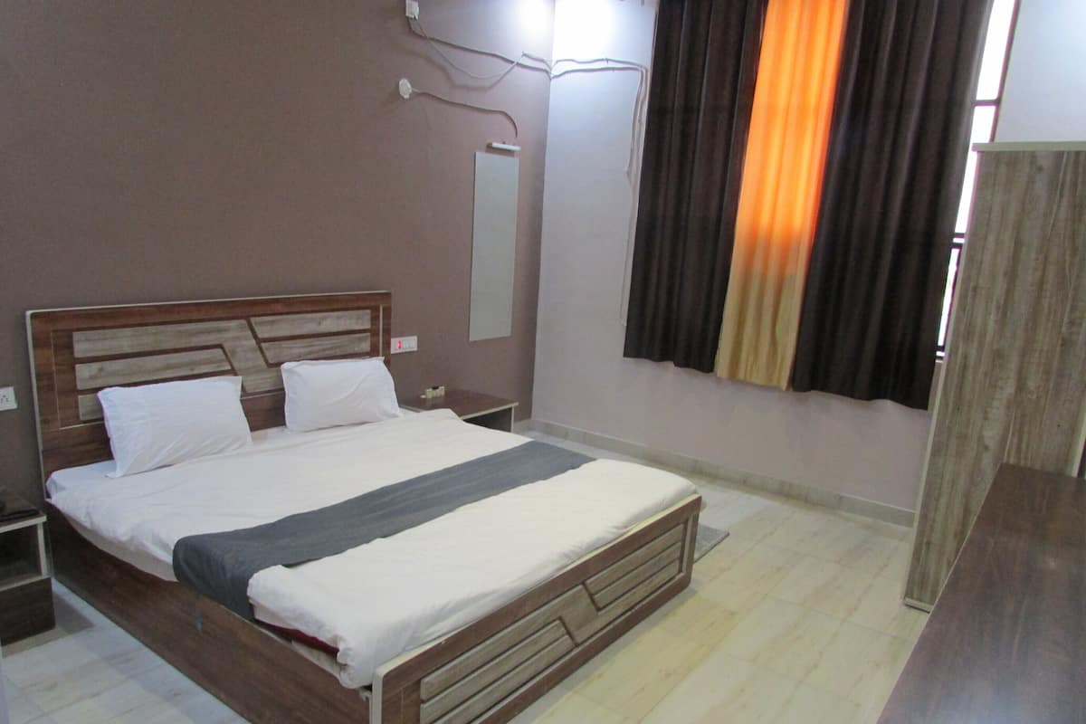 A bedroom with a wooden bed, a nightstand, a bedside table, a mirror, and a window with curtains.