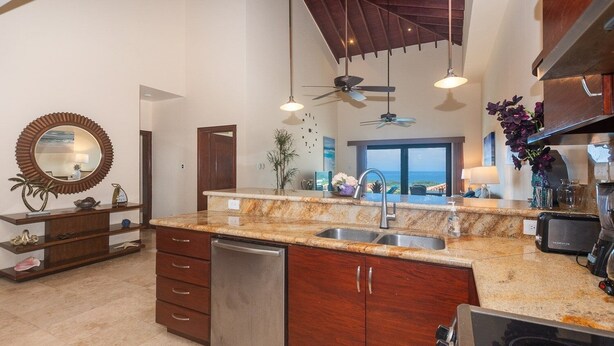 A modern kitchen with granite countertops, stainless steel appliances, and wooden cabinetry. - Pristine Bay 1205 2 Bedroom Villa (Roatan)