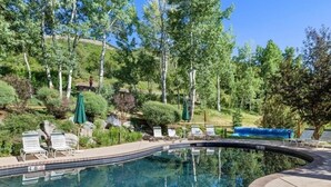 A swimming pool with lounge chairs and a natural landscape in the background. - Remodeled Snowmass Pet-Friendly Modern 1BR Condo - G125 (Snowmass Village)