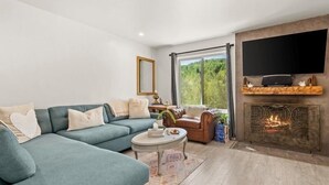 A modern living room with a blue sofa, a small round table, and a fireplace. - Remodeled Snowmass Pet-Friendly Modern 1BR Condo - G125 (Snowmass Village)