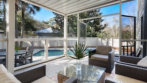 A covered patio with wicker furniture, a glass table, and a view of a swimming pool. - Old Seagrove "Angel's Share" 4BR | Sleeps 10 | Heated Pool | Updates | 🐶 (Santa Rosa Beach)
