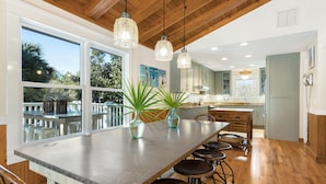 A modern kitchen with a large island, bar stools, and pendant lighting. - Old Seagrove "Angel's Share" 4BR | Sleeps 10 | Heated Pool | Updates | 🐶 (Santa Rosa Beach)