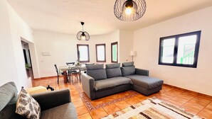 A modern living room with a grey sectional sofa, a patterned rug, and a dining area with a table and chairs.