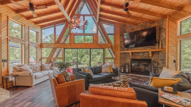 A spacious living room with a fireplace, large windows, and wooden beams.