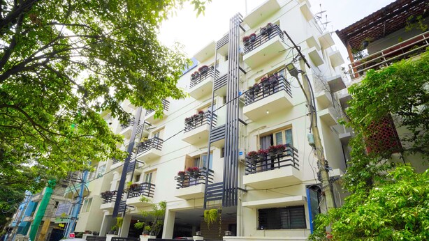 A multi-story residential building with balconies, a gated entrance, and parked cars. - Mystic Felicity Inn (Bengaluru)