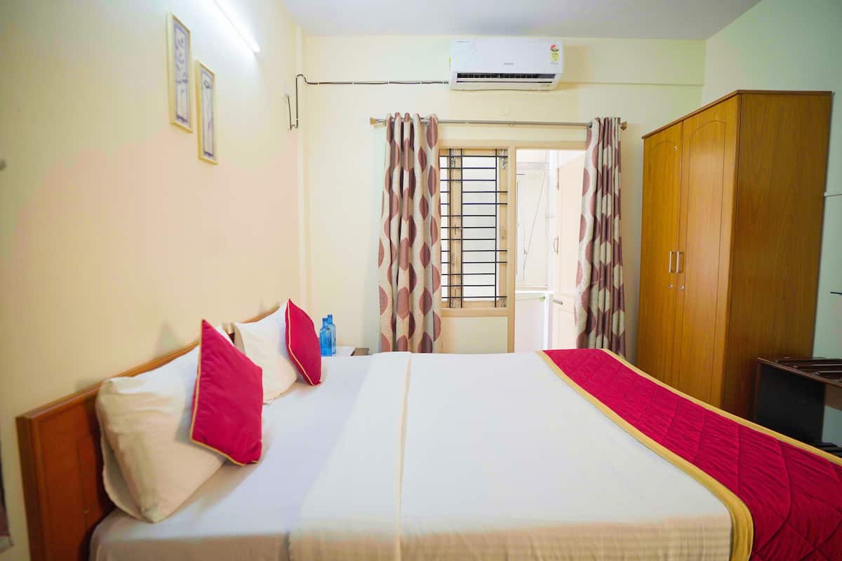 Quarto de hotel com cama, guarda-roupa, ar condicionado e cortinas.