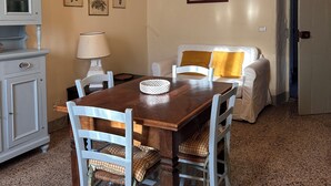 Un coin repas avec une table en bois et des chaises blanches, un meuble blanc et un luminaire suspendu.
