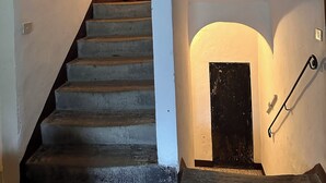 Un escalier avec une main courante en bois sombre menant à une porte sombre située en haut.
