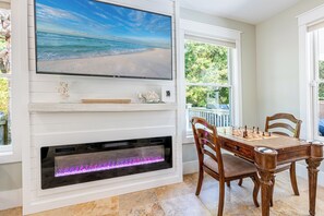 Ein Wohnzimmer mit Kamin, Wandfernseher und einem Schachtisch.