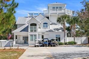 Une maison à deux étages avec un balcon, portant le numéro 241, et plusieurs voiturettes de golf garées devant.