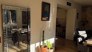 Un salon spacieux doté d’un parquet en bois, d’un grand miroir et de plusieurs cactus en pot.