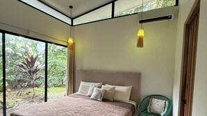 Un dormitorio moderno con una cama grande, una silla verde y vistas al exterior.