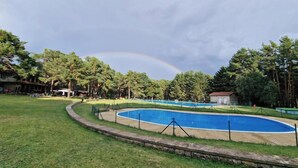 Une piscine entourée d’une pelouse et d’arbres.