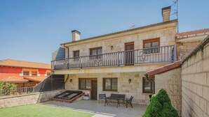 Un bâtiment à deux étages doté d’un balcon, d’un petit patio avec des meubles d’extérieur et d’une pelouse bien entretenue.